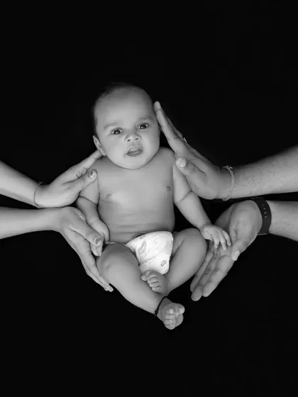 This artistic black and white photograph symbolizes the circle of love and protection surrounding a new baby. It's a powerful, conceptual shot that we create to represent the strength of family bonds.