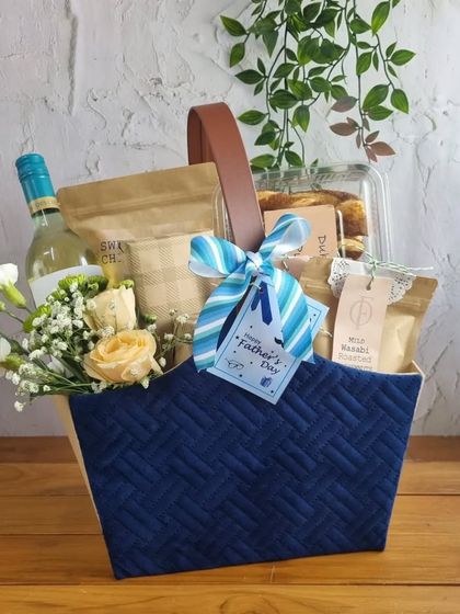 A premium Father's Day hamper in a deep blue basket, including a bottle of non-alcoholic wine and fresh flowers.