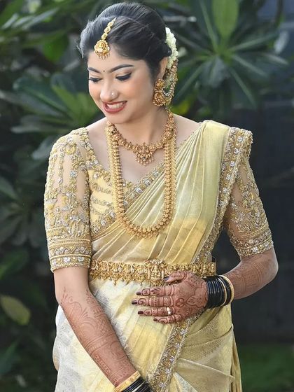 A full portrait of the bride in her gold saree, showing the beautiful drape and the way the light catches the fabric. This is a timeless look for any bride who wants to feel like royalty.