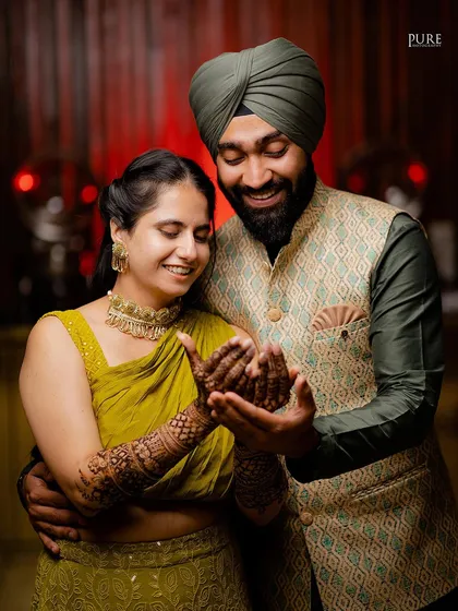 The couple admiring the bride's beautiful Mehndi design together. A lovely moment of shared appreciation and connection.
