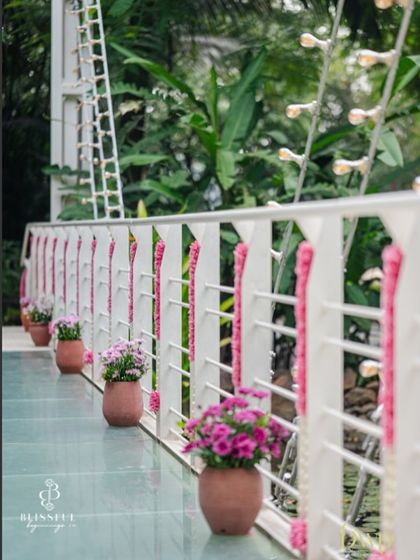 A closer look at the floral details on the bridge railing. The simple pink garlands and potted flowers add a touch of color and elegance to the modern white structure.
