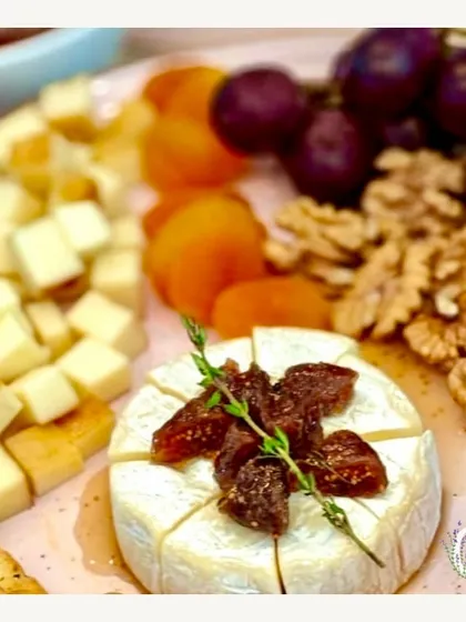 A cheese board that made it to a Sunday movie night. This image features a wheel of brie topped with figs, alongside cubed cheese, nuts, and dried apricots.