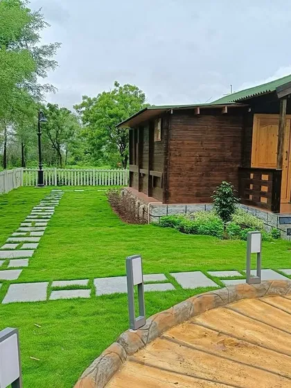 The finished farmhouse garden, featuring a lush lawn that meets a custom stone pathway. The white picket fence and modern path lighting complete the clean, rustic look.