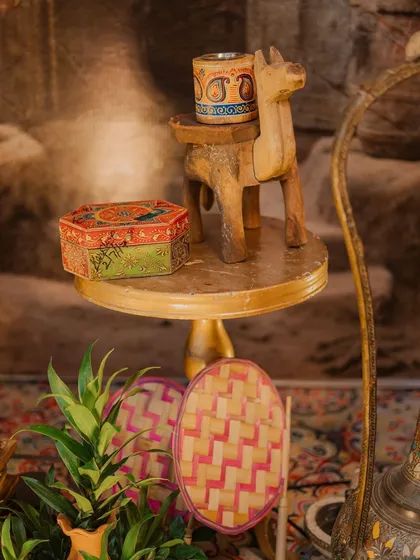 A small detail from the Punjabi night decor. A hand-painted box and a wooden camel figurine sit atop a small table, adding to the authentic and rustic charm of the theme.