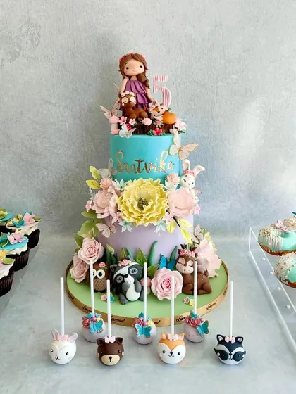 This woodland-themed dessert table for Saatvika's birthday was so elaborate and beautiful. The cake is adorned with sugar flowers and cute woodland creatures, and we made matching cake pops, donuts, and cupcakes.