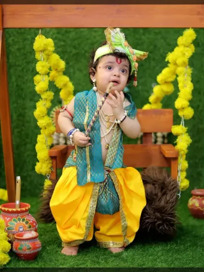 A full-length portrait of a baby in an elaborate Krishna costume, showing the complete look from the crown to the dhoti.