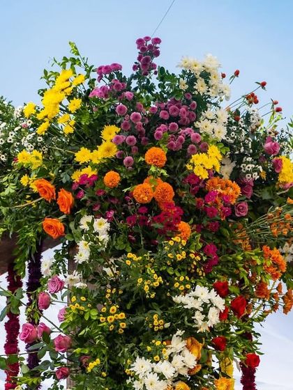 The vibrant floral topper of the mandap pillar, a beautiful mix of textures and colors against the sky.