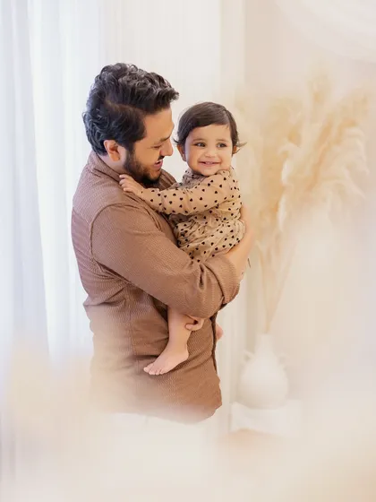 A father's gentle hold. This portrait captures the tender bond between a dad and his one-year-old daughter, filled with warmth and affection.