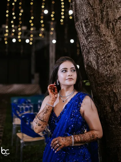 A classic bridal portrait taken during the Sangeet, with the bride looking elegant against the backdrop of ambient lights and a rustic tree.