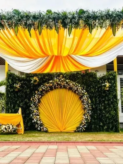 For this outdoor naming ceremony, I designed a vibrant and sunny theme. The setup features a grand arch of greenery, a backdrop of draped yellow and white fabric, and a central floral medallion, creating a beautiful focal point on the lawn.