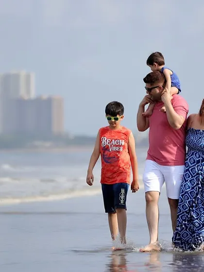 A candid shot of a family enjoying a walk by the sea. Our outdoor lifestyle sessions are all about capturing your family's unique bond in a relaxed, natural setting.