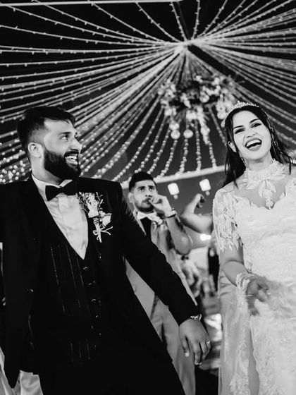 The couple and their guests dancing under a canopy of lights. This black and white shot captures the fun and communal celebration of the wedding reception.