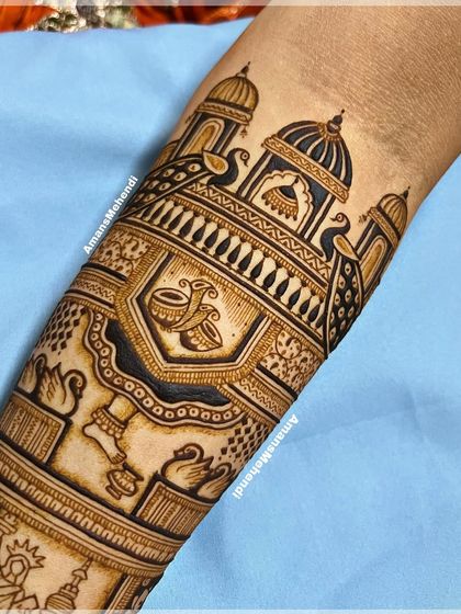 A close-up of a bridal arm band featuring dancing figures, swans, and dhol players. The design celebrates the joy and festivity of a wedding.