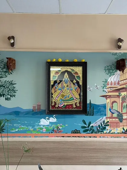 I designed this mural to incorporate a client's existing framed artwork. The scenic wallpaper with swans and a lakeside palace creates a beautiful, integrated backdrop for their deity's picture.