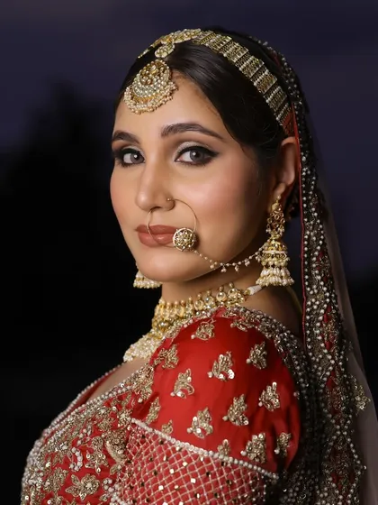 A close-up profile of a beautiful bride. This shot highlights the sharp, defined eye makeup and the flawless contouring that sculpts the face beautifully.