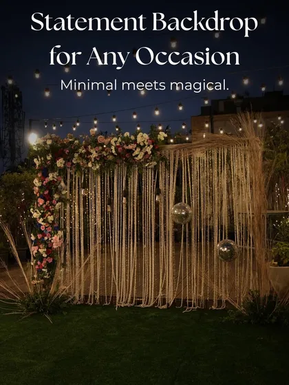 A minimal yet magical statement backdrop for any occasion, featuring a macrame curtain, disco balls, and a floral arrangement under string lights.