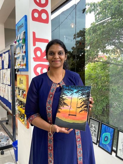 A participant proudly displays her sunset painting of a swing between two palm trees. It's a beautiful reminder of a peaceful moment.
