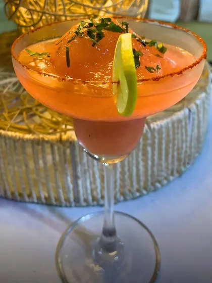 A close up of the Peru Paprika mocktail, showing the slushy texture and the beautiful garnish. The spicy rim and fresh lime slice add to the visual appeal and flavour complexity.