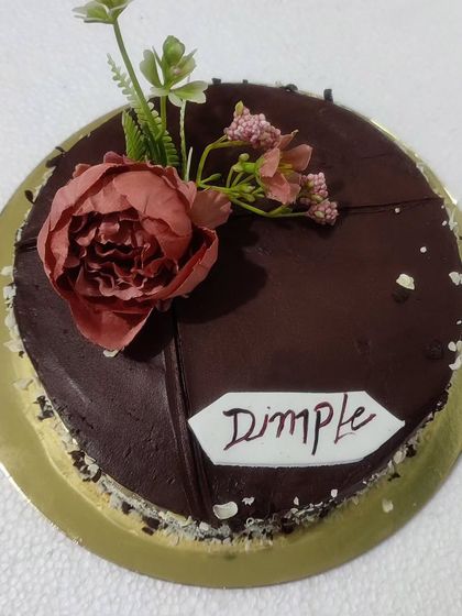 A simple chocolate cake with a single, elegant sugar flower.