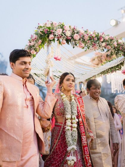 The bride's grand entrance under a phoolon ki chadar. This shot captures the emotion and tradition of the bridal procession, a beautiful moment from a North Indian wedding.
