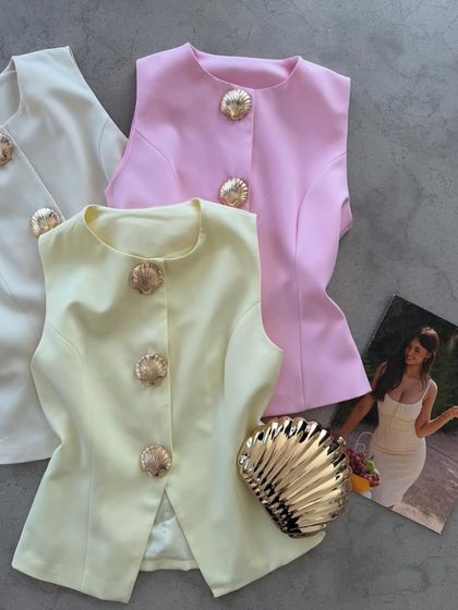 A flat-lay of my sleeveless waistcoats in off-white, pink, and pale yellow. Each one features beautiful seashell-inspired gold buttons for a unique touch.