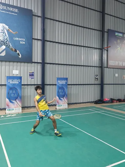 Another young athlete in action during the Yonex event at my academy. The professional setup, complete with branding from partners like Yonex and posters of stars like Lakshya Sen, inspires my players.