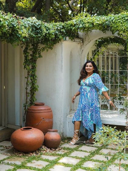 A woman poses in the beautiful, green courtyard of a Fort Kochi property. My trips include stays at aesthetic and culturally rich places that add to the overall experience.