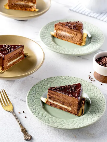 Slices of chocolate mousse cake elegantly plated. The composition uses repeating elements and soft colors to create a visually pleasing pattern, ideal for showcasing a signature dessert.