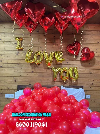 This decoration focuses on the area above the bed, with "I LOVE YOU" foil balloons and dozens of red heart-shaped foil balloons hanging down, creating a curtain of love.