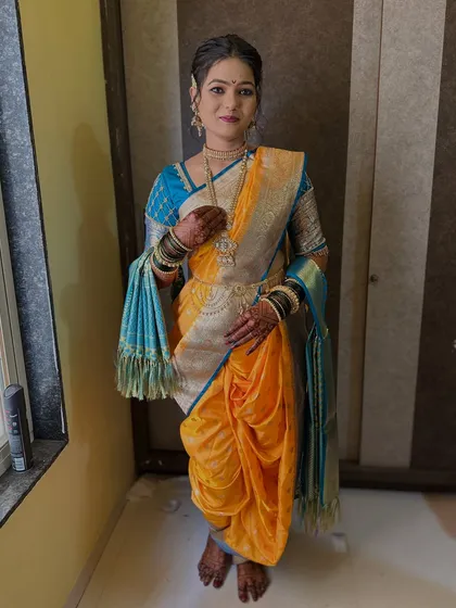 A full-length view of the 'Marathmol saptapadi' look, showing the perfectly draped yellow Nauvari saree with a blue border and traditional jewellery.