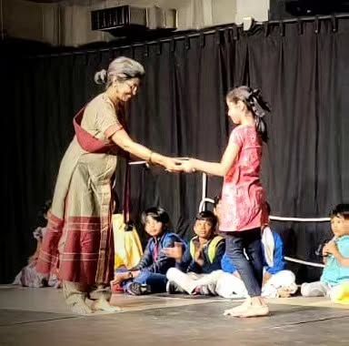 A facilitator shares a moment of connection with a student on stage. Our approach is nurturing and encouraging, helping each child to find their confidence.