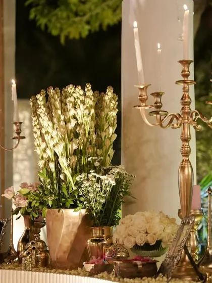 A close-up of the anniversary decor, showing the warm glow of the candles on the brass candelabras and the fresh white tuberoses, creating a classic and romantic ambiance.