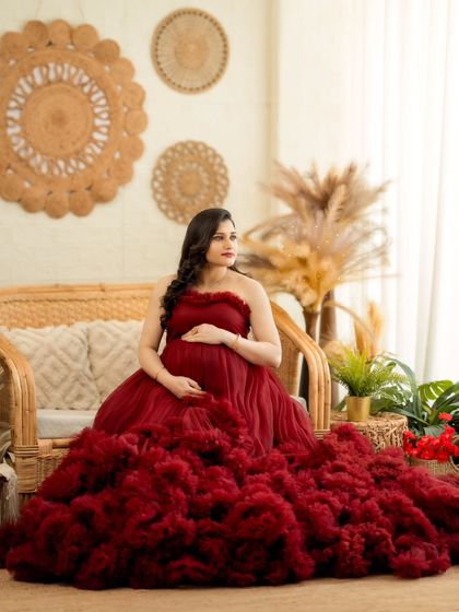 A serene portrait of the mom-to-be seated on a cane sofa, looking absolutely radiant in red.