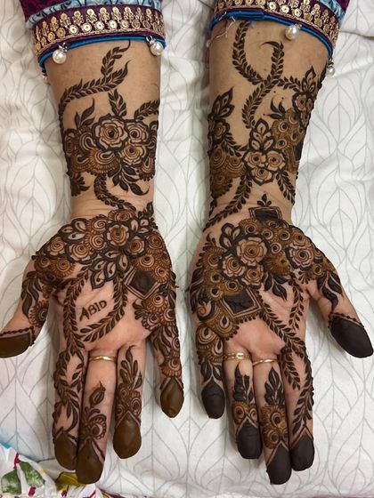 An intricate floral vine design that includes the name 'Abid' cleverly integrated into the pattern on the palm.