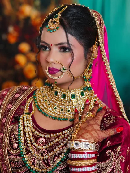 A close-up of a royal bridal look. The focus is on the flawless base, defined eyes, and how the makeup complements the heavy kundan and emerald jewelry.