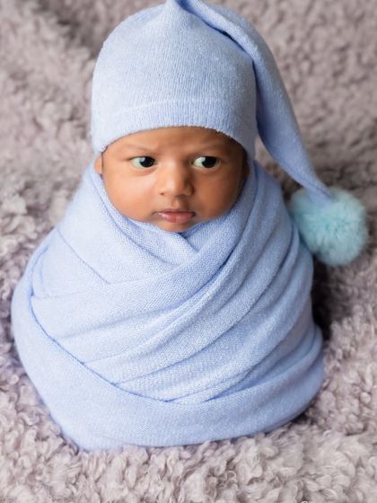 A precious awake moment from the same session, this little one looks around with curiosity from his cozy blue wrap.