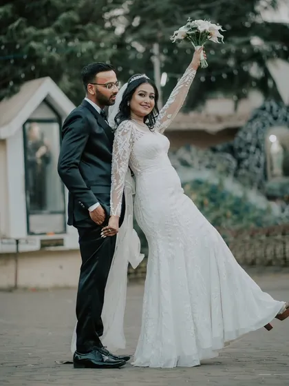 A fun and celebratory portrait of the couple outside the church. The bride joyfully raises her bouquet, celebrating their marriage.