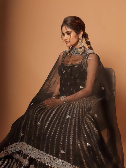 A full-length seated portrait of Aaditi Pohankar. The intricate details of her lehenga are matched by the elegant makeup and the elaborate braided hairstyle, creating a complete, stunning look.