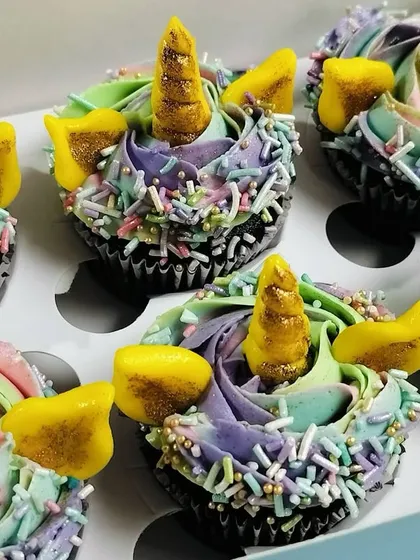 A close-up shot of a box of six unicorn cupcakes. You can see the rich chocolate cupcake base beneath the colorful frosting, promising a delicious treat that tastes as good as it looks.