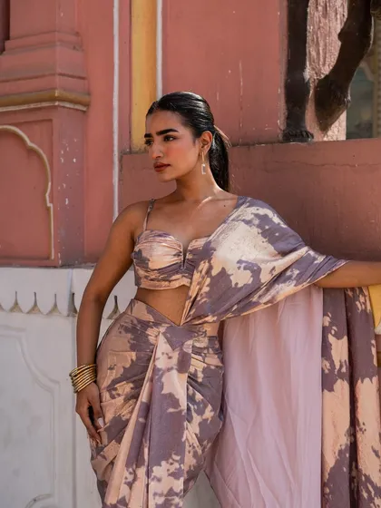 Part of our Pastel Pink Edit, this pre-draped dhoti saree features a modern tie-dye print and a stylish bustier blouse.
