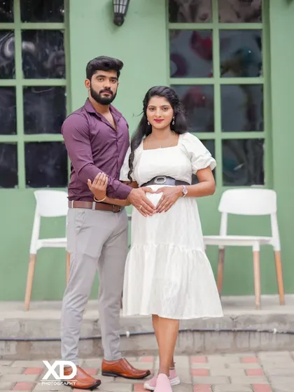 A classic couple's pose, with their hands joined to form a heart on the baby bump.