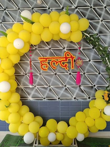 For a more modern Haldi decoration, we offer this circular balloon arch. The bright yellow balloons create a cheerful frame, with the "Haldi" sign suspended in the center for a fun photo booth.