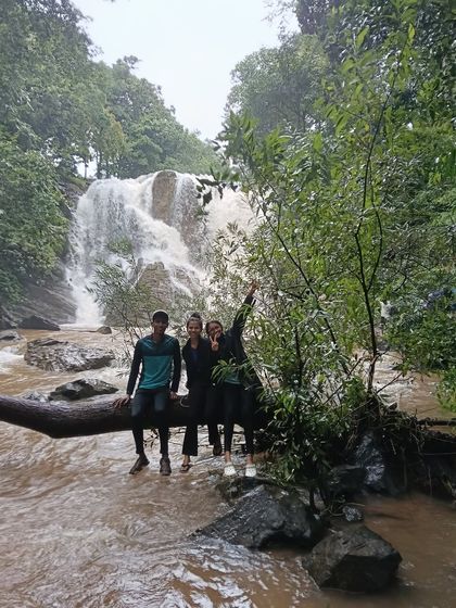 Three friends sitting on a log over a stream, a classic moment from our Bandaje trek.