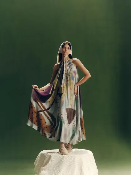 An artistic shot for Cord, with the model standing on a prop to create a statue-like pose, showcasing the flow of the dress.