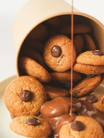 Another shot of our crisp and sweet mini chocolate chip cookies, getting covered in a smooth cascade of melted chocolate.