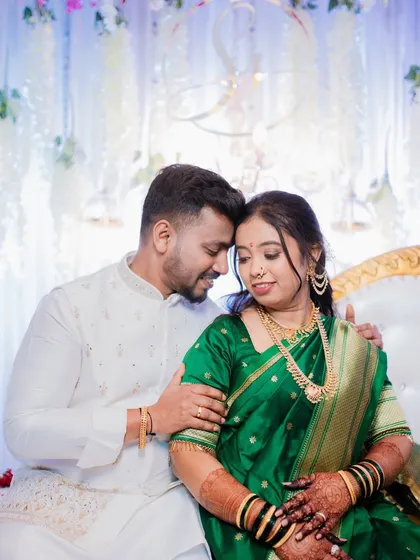 A classic Maharashtrian engagement portrait. The bride's beautiful green Paithani saree and traditional jewelry are complemented by the couple's gentle and happy connection, showcasing a moment of quiet celebration.