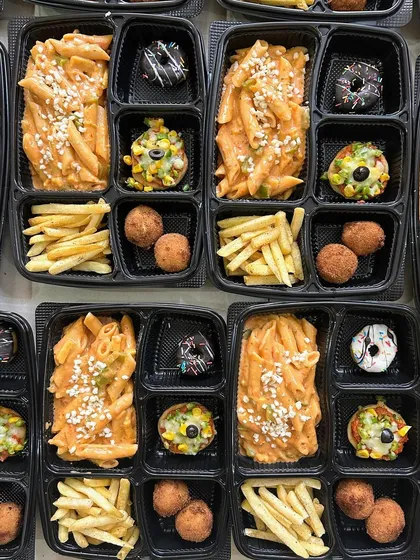 A close-up of my party meal boxes with creamy pink sauce pasta, crispy french fries, cheese balls, mini pizzas, and a mini doughnut.