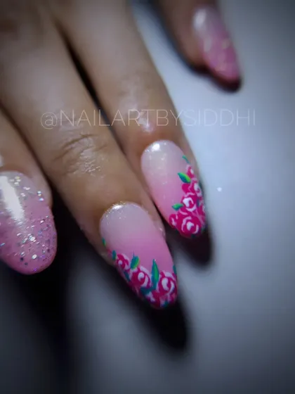 A close-up of the delicate pink roses painted along the edge of the nail.
