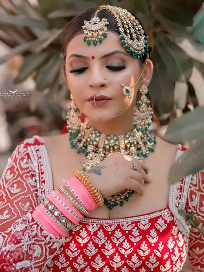 A close-up of the bride with her eyes closed, highlighting the flawless makeup and the heavy, green-beaded jewelry.