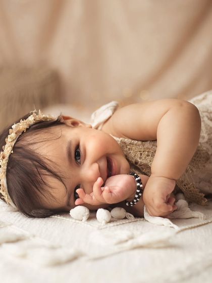 I just can't handle this level of cuteness. Her shy smile and playful pose on the soft blanket melt my heart every time.